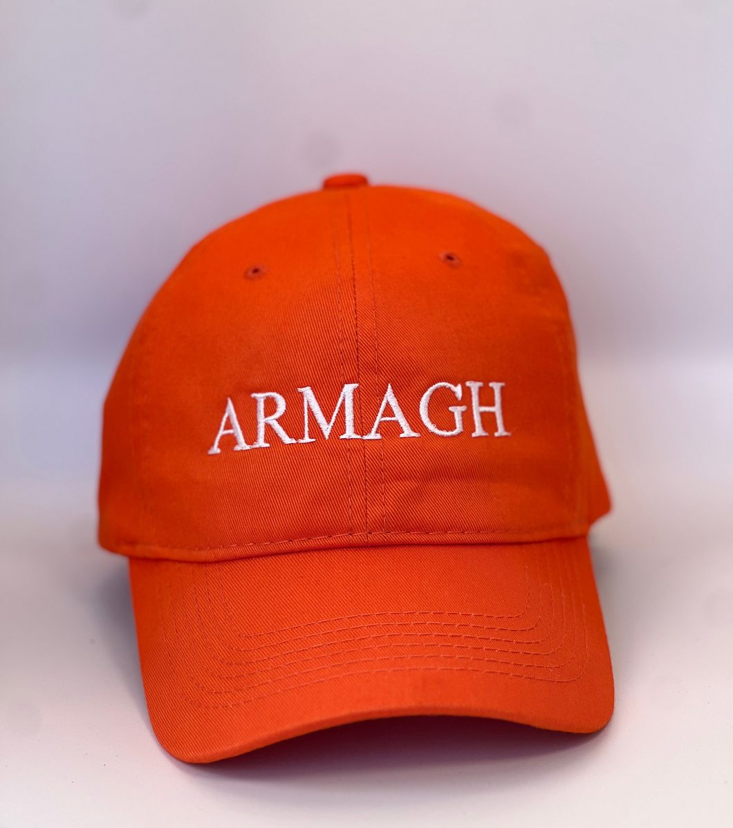 Orange baseball cap with 'ARMAGH' in white embroidery thread. Adjustable back strap with metal clasp.