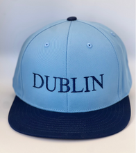 Load image into Gallery viewer, Blue and navy trucker style baseball cap with &#39;Dublin&#39; embroidered in navy thread. Adjustable  snap back strap.
